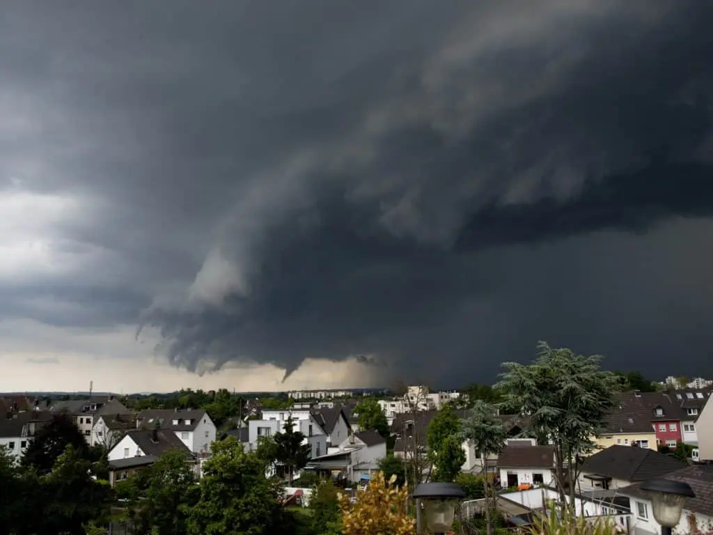 Dark storm clouds looming over residential homes, indicating severe weather risks and potential storm damage relevant to homeowners in Southeast Michigan.